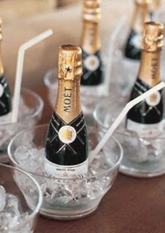 several bottles of champagne in small glasses on a table with ice cubes and spoons