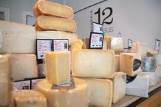 several different types of cheese stacked on top of each other in a display case at a store