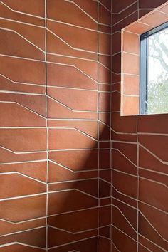 the corner of a bathroom with a window and brick wall in it's corner