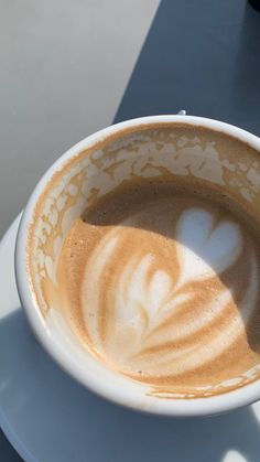 a cup of coffee on a saucer with the shadow of a heart in it