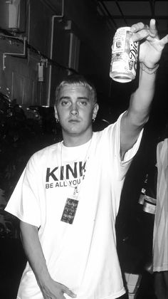 a young man holding up a can of beer