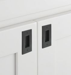 two black and white knobs are on the side of a cabinet door that is closed