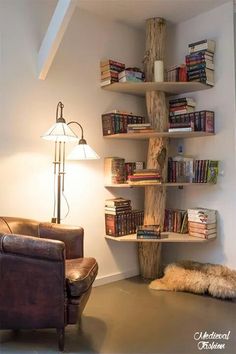 a living room with a leather chair and bookshelf in the corner next to a lamp