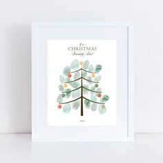 a christmas tree with leaves and berries is shown in a white frame on a table