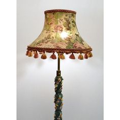 a lamp that is sitting on top of a wooden base with tasseled trim