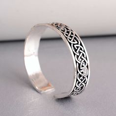 a silver ring with an intricate design on the inside and outside, sitting on a table