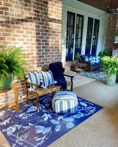 a blue and white rug on the front porch next to a wooden bench with striped pillows