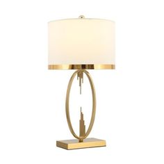 a table lamp with a white shade on it and a gold metal frame around the base