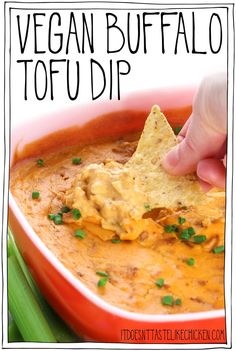 a hand dipping a tortilla chip into a bowl of vegan buffalo tofu dip