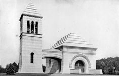 an old black and white photo of two tall buildings with arches on each side, one has a clock at the top