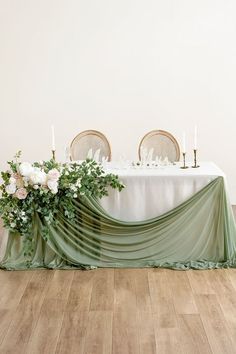 the table is set with white flowers and greenery