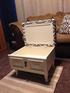 an open trunk sitting on top of a rug next to a couch