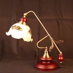 a desk lamp that is on top of a wooden base with a white glass shade