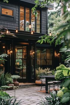 a black house surrounded by greenery and lights