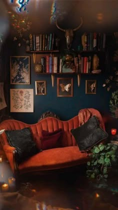 a living room filled with furniture and lots of books on the shelves above it is a red couch surrounded by plants