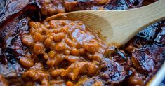 a wooden spoon in a pot filled with baked beans