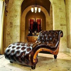 a brown leather chaise lounger sitting in front of a mirror and chandelier