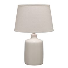 a white table lamp with a beige shade on the base and a light bulb attached to it