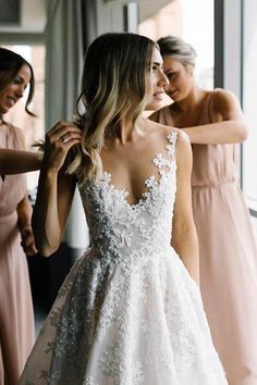 a woman in a wedding dress getting ready for her bridesmaid to get dressed