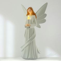 an angel figurine holding a lit candle