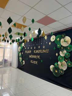 an office decorated with green and white paper fans hanging from the ceiling, in front of a black wall