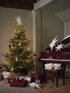 a decorated christmas tree sitting next to a piano