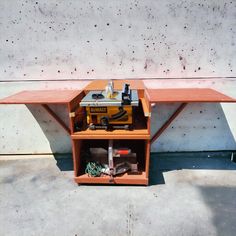 a workbench with tools on it sitting in front of a concrete wall