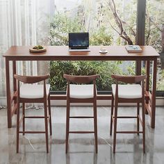 a table with four chairs and a laptop on it in front of a large window