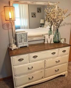 a bedroom with a dresser, mirror and lamp