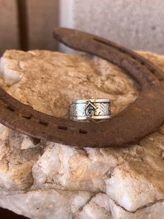 a silver ring sitting on top of a piece of rock next to a horseshoe shaped object