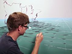 a man in glasses is drawing on a wall