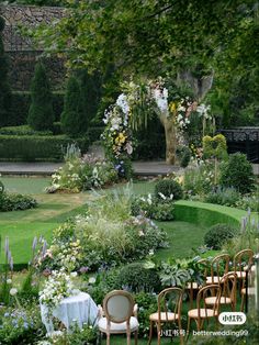 there are many chairs and tables in the garden with flowers around them on the lawn