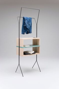 an open shelf with clothes on it and a blue shirt hanging from the rack next to it