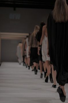 several models walk down the runway in black dresses