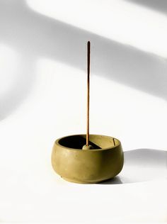 a small bowl with a wooden stick sticking out of it's center, sitting on a white surface