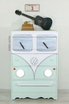 an old vw camper dresser with a guitar on top and books atop it