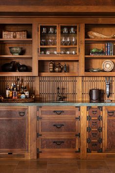 a kitchen with lots of wooden cabinets and glassware on the counter top in front of it