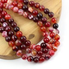 two strands of red and black beads on a wooden tray