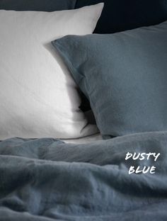 a bed with two pillows on top of it next to a blue blanket and pillow