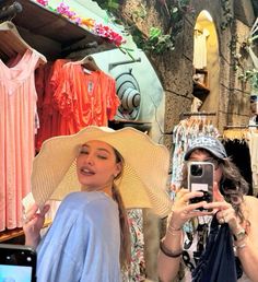 two women in hats are taking pictures with their cell phones while another woman is holding up her phone