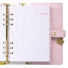 a pink planner is open on top of a white book with gold trimmings