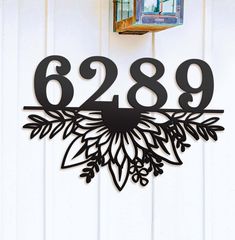 a clock that is on the side of a door with numbers and leaves around it