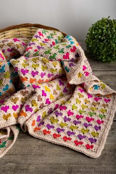 a crocheted blanket sitting on top of a wooden floor next to a potted plant