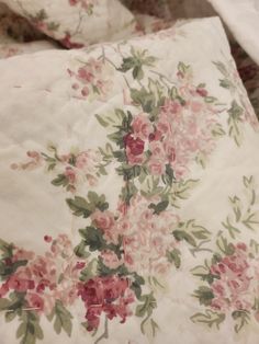 an image of a flowered bed sheet with pink and green flowers on white sheets