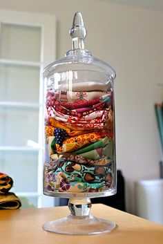 a glass jar filled with lots of different types of fabric