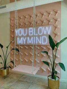 a neon sign that says you blow my mind in front of some potted plants