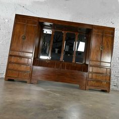 a large wooden desk with mirrored doors on it's front and back sides in an empty room