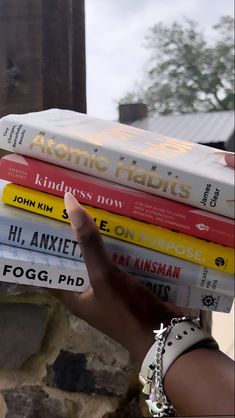 a stack of books sitting on top of each other in front of a brick wall