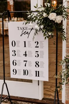 a sign with numbers and flowers on it in front of a door that says take seat