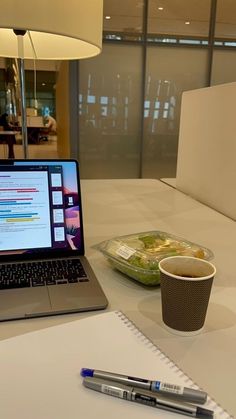 an open laptop computer sitting on top of a table next to a cup of coffee